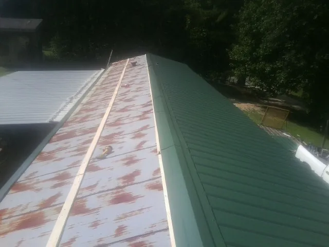 Old rusted panels beside newly installed green metal roofing — Wind Damage Roof Repair by Roofing Brothers in New Milford