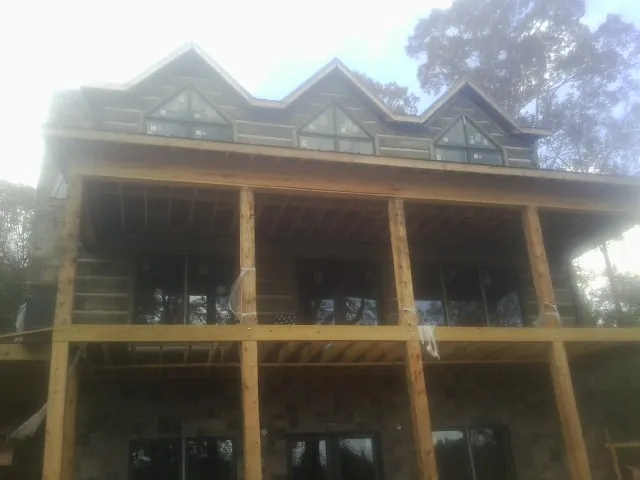 Dormers and porch framing on a large log home under construction — Roof Coating work by our crew in New Milford